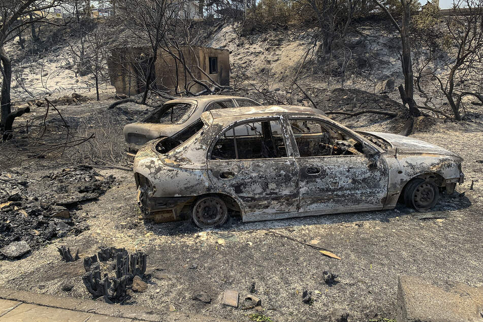 Verbrannte Autowracks stehen nach katastrophalen Waldbränden auf einer Straße der griechischen Insel Rhodos.