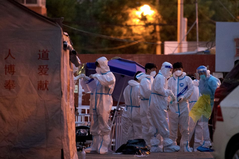 Gesundheitspersonal mit Schutzausrüstung ist am Eingang eines eingezäunten Wohngebiets in Peking zu sehen.