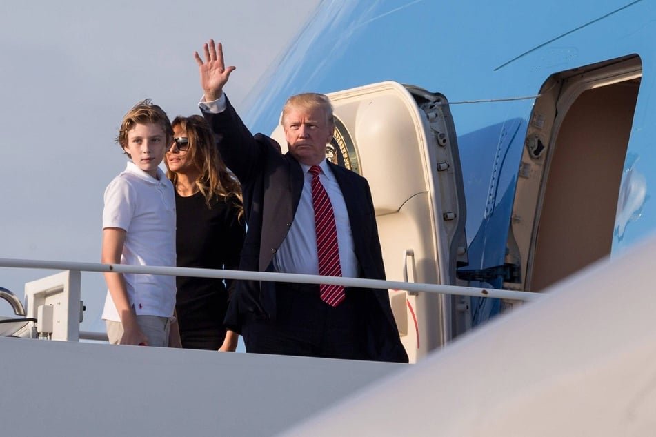Donald Trump waving as he boards Air Force One with his wife Melania Trump, and their son Barron (l.) at the Palm Beach International Airport in Florida on November 26, 2017.