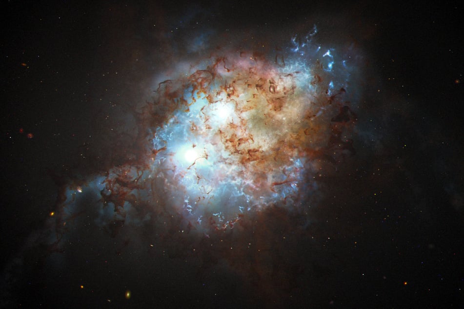 An artist's depiction shows the brilliant glare of two quasars residing in the cores of two galaxies that are in the chaotic process of merging.