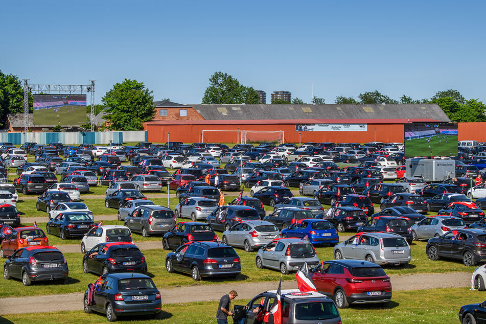 Fußballfans verfolgen auf dem Parkplatz der MCH-Arena das Spiel zwischen dem FC Midtjylland und dem AC Horsens, welches auf eine Leinwand übertragen wird.