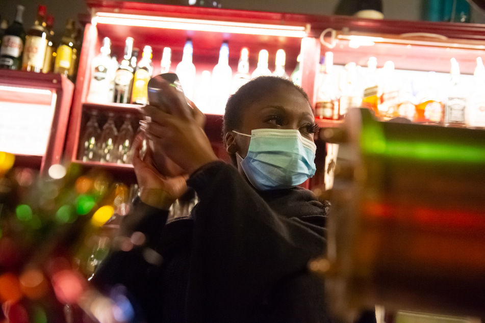 Eine Barkeeperin steht mit Mund-Nasen-Schutz hinter dem Tresen einer Bar im Schanzenviertel.