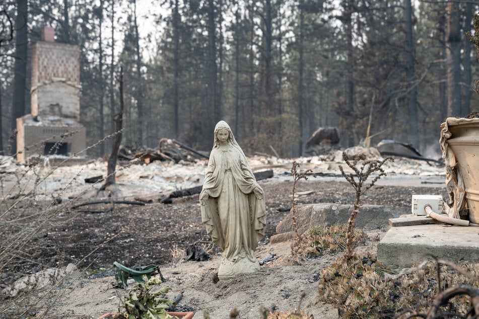 A Virgin Mary statue remains untouched in front of a burned out residential home in the Balboa neighborhood of Spokane, Washington, on August 2, 2026.
