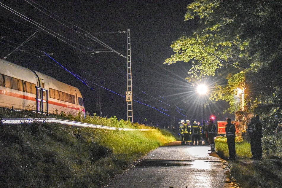 Einsatzkräfte stehen am Abend an der Bahnlinie bei Schwäbisch Gmünd. Zwei Waggons eines ICE mit 185 Passagieren an Bord sind nach einem Erdrutsch entgleist.