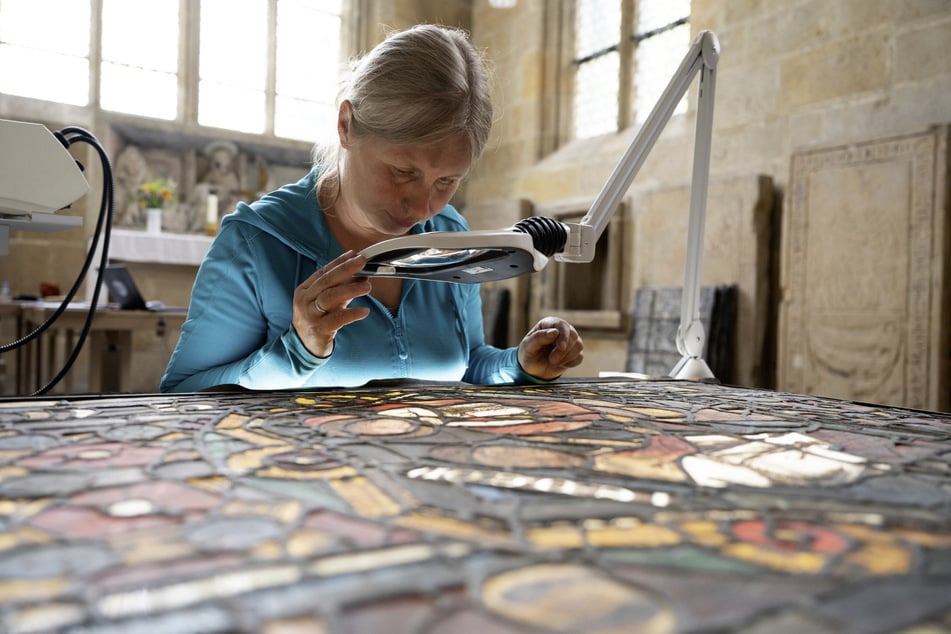 Diplomrestauratorin Kathrin Rahfoth begutachtet auf einem Leuchttisch ein mittelalterliches Glasfenster.