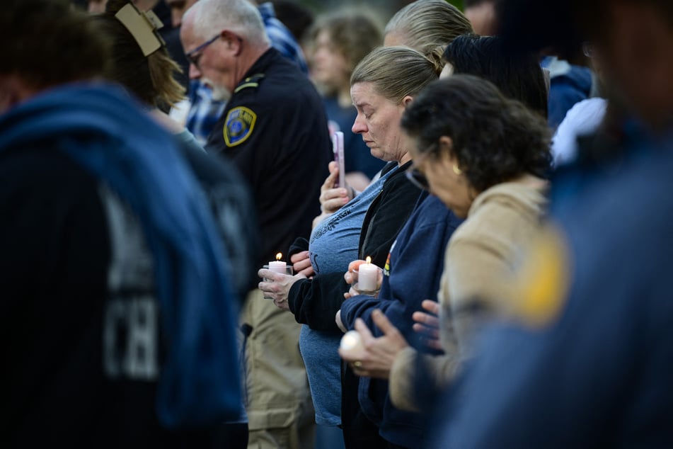 Community members hold candles and bow their heads in prayer during a vigil at R.A. Long Park following a fatal chemical storage tank failure on May 26, 2026, in Longview, Washington.