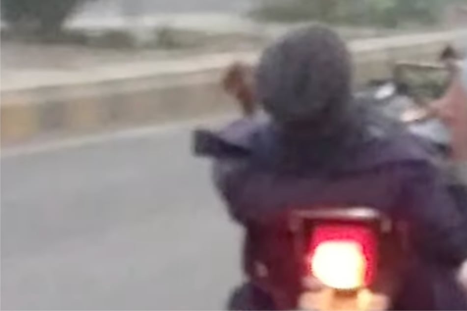 Biker guckt Film während der Fahrt und steuert Motorrad mit den Füßen