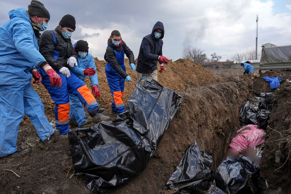 Tote werden in ein Massengrab am Rande der ukrainischen Stadt Mariupol gelegt, da die Menschen ihre verstorbenen Angehörigen wegen des schweren Beschusses durch die russischen Streitkräfte nicht begraben können.