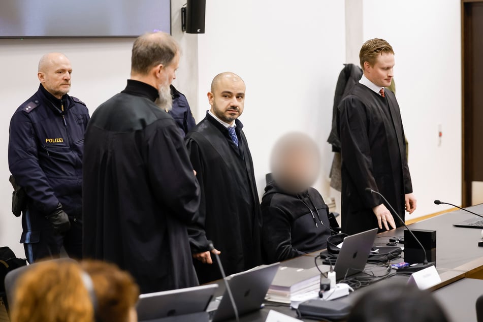 Der Angeklagte sitzt zwischen seinen drei Verteidigern (v.l.n.r.) Martin Heising, Serkan Alkan und Dr. Florian Münch.