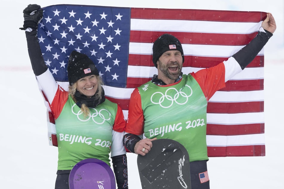 Team USA's Lindsey Jacobellis (l.) and Nick Baumgartner at the flower ceremony after their gold medal win in mixed team snowboard cross at the 2022 Olympic Winter Games.