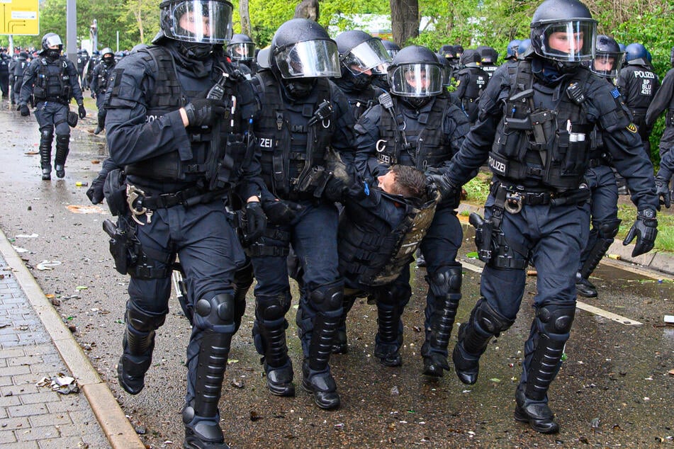 Polizisten tragen einen Kollegen weg. Bei Ausschreitungen gab es über 200 Verletzte.