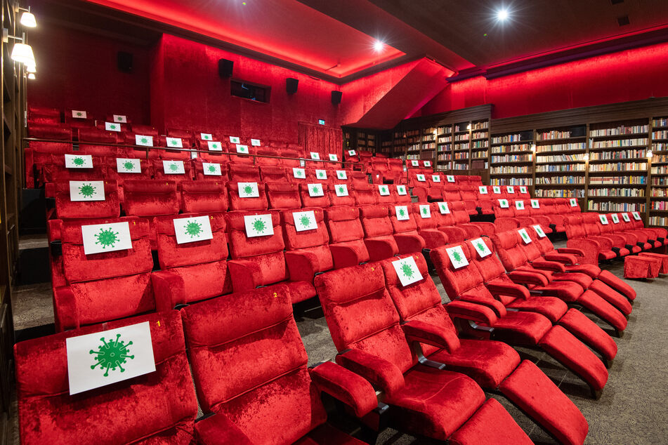 Einzelne Sitzplätze in einem Kinosaal sind mit Zetteln mit aufgedrucktem angedeuteten Virus-Symbol abgesperrt, damit Kino-Besucher einen Abstand von 1,5 Meter zueinander einhalten können.