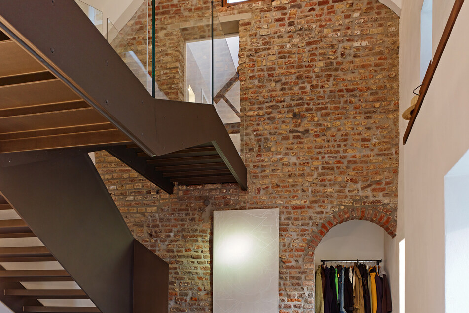 Ein großer Treppenflur mit Backsteinwand profitiert von der Hochleistungsdämmplatte UdiCLIMATE, da Wärme besser gehalten wird.