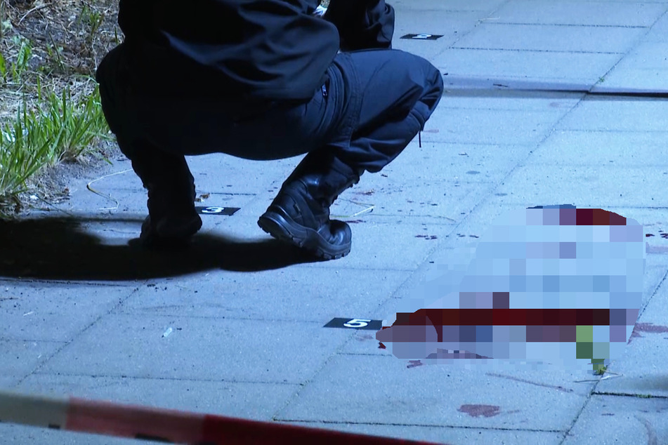 Ein Polizist kniet neben einer Blutlache. Ein 45-jähriger Mann ist bei einem Messerangriff auf St. Pauli lebensgefährlich verletzt worden.