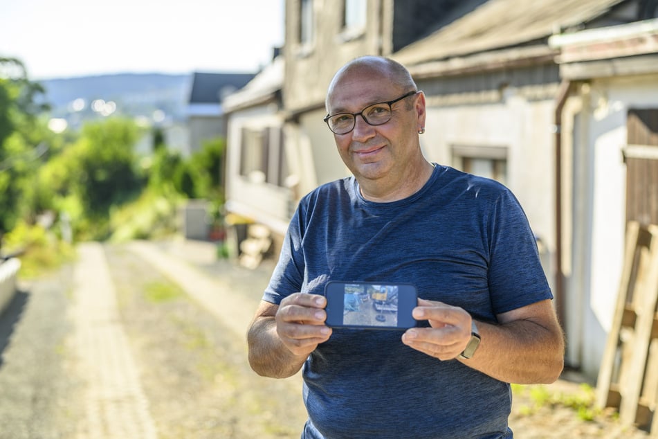 Tino Schlott (58) zeigt ein Foto der verengten Zufahrt. Die gehört nun allerdings der Vergangenheit an.