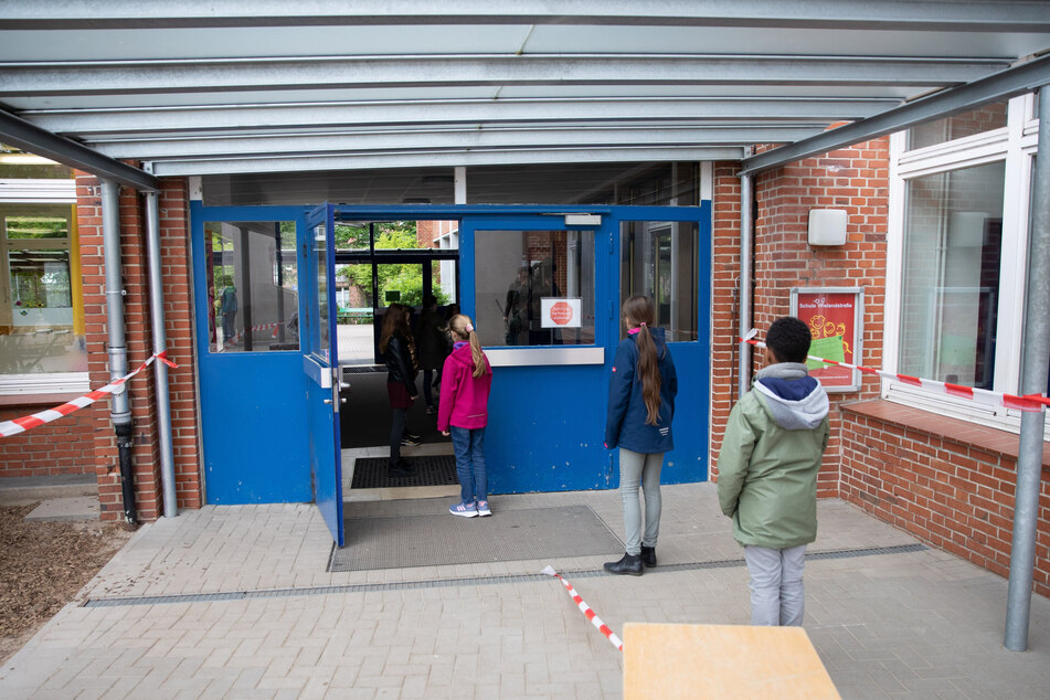 Schüler einer 4. Klasse stehen nach den geltenden Abstandsregeln vor ihrer Schule.