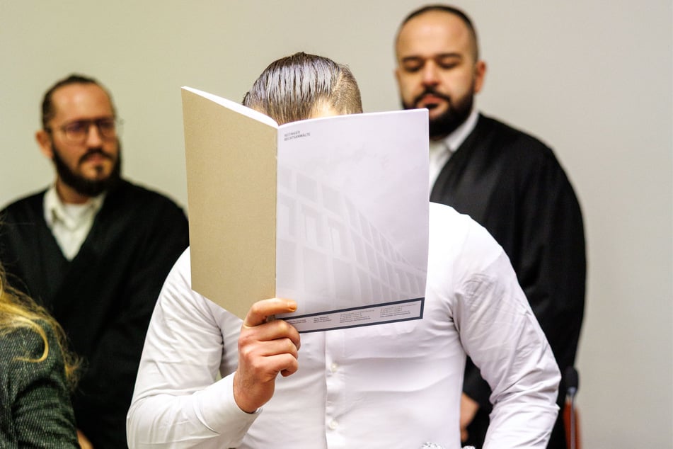 Der Mann versteckte sein Gesicht hinter einem Ordner.