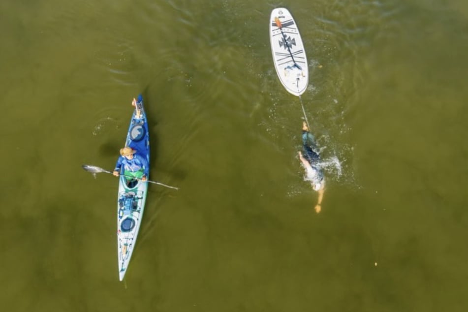 Beim Donau-Schwimmen zieht der Sachse stets ein SUP-Board hinter sich her. Thorsten Arp (l.) im Kajak begleitet ihn und warnt bei Gefahr, sodass er aufs SUP umsteigen kann.