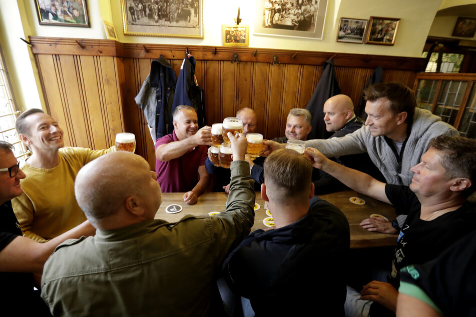 Tschechen stoßen fröhlich mit Bier in einer traditionellen Bierkneipe an.