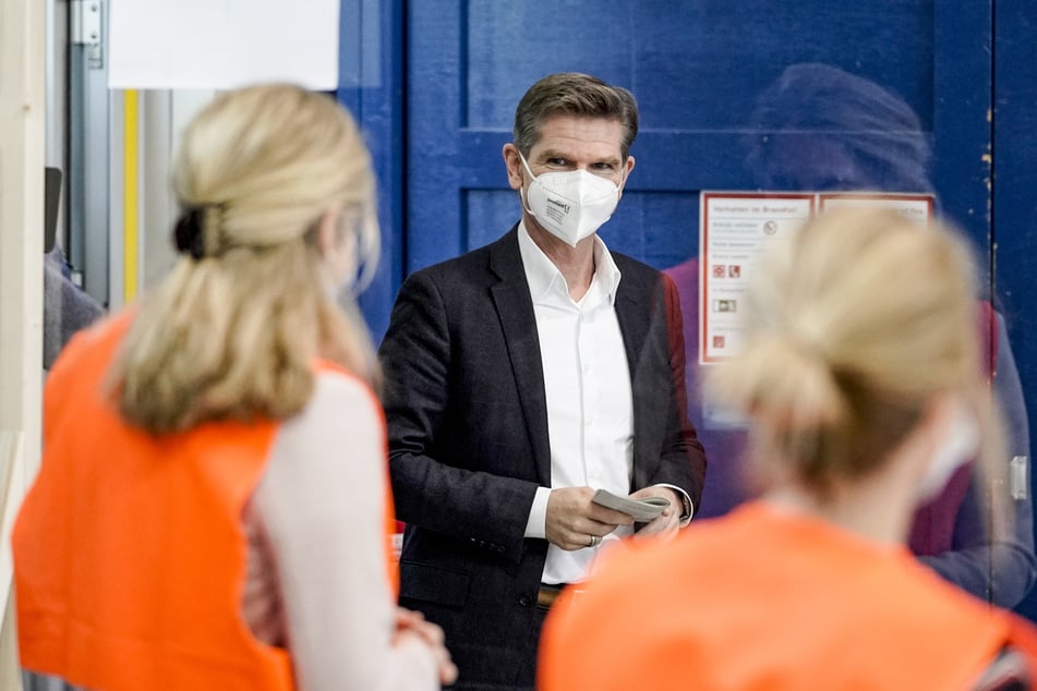 Heiner Garg (FDP), Gesundheitsminister von Schleswig-Holstein, lässt sich in einem künftigen Corona-Impfzentrum in den Messehallen in Husum eine Station erklären.