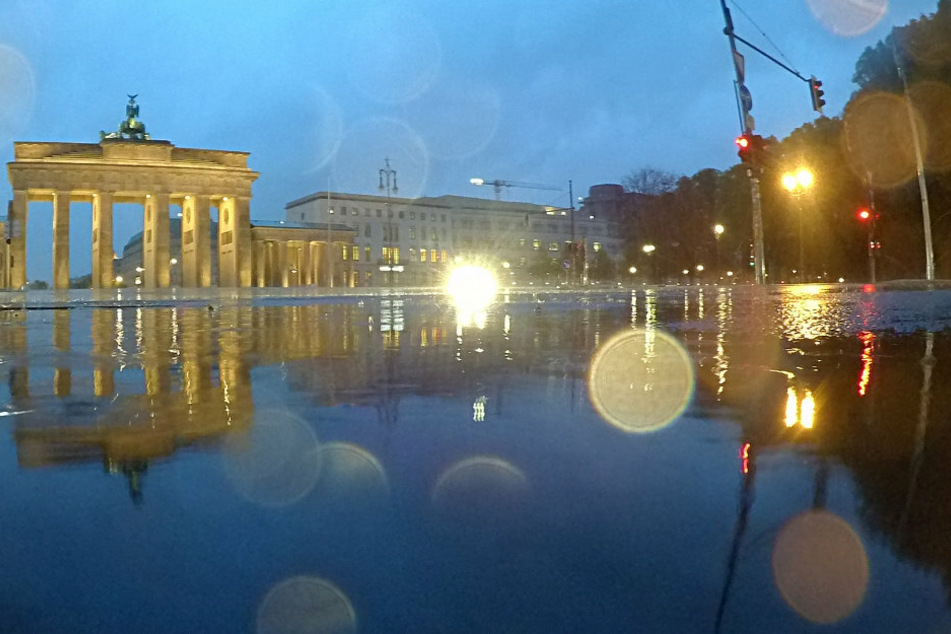 Das Brandenburger Tor spiegelt sich in einer Regenpfütze.