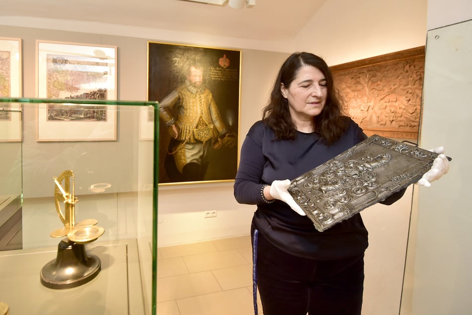 Ausstellungs-Kuratorin Andrea Kramarczyk hält das Wappen der Annaberger Münzerfamilie.