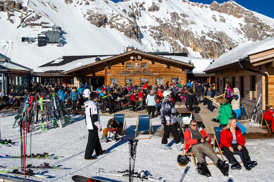 Skifahrer genießen vor einer Hütte in Garmisch-Partenkirchen das gute Wetter. (Archiv)
