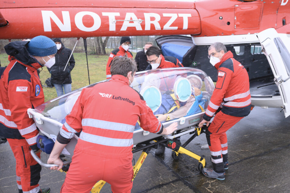 Mitarbeiter der Deutschen Rettungsflugwacht (DRF) heben anlässlich eines Pressetermins die Isolationstrage "Epi-Shuttle" in einen Rettungshubschrauber. Die eingekapselte Isolationstrage ermöglicht den Transport ansteckender Patienten zur weiteren Behandlung, ohne dass sich Sanitäter einem Infektionsrisiko aussetzen.