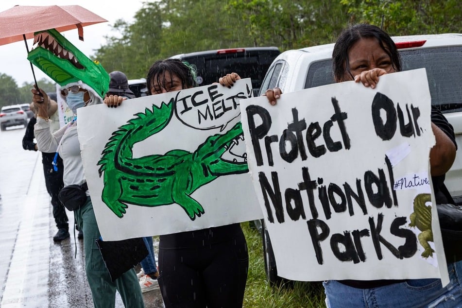 Protesters raise signs reading "Protect Our National Parks" and "ICE Melts!" during a demonstration against the proposed construction of an immigration detention facility in the Florida Everglades dubbed "Alligator Alcatraz."