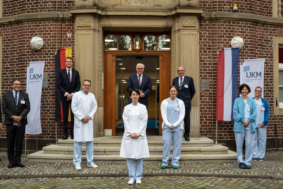 Bundespräsident Frank-Walter Steinmeier steht vor einem Gebäude der Uniklinik zwischen Ärzten und Pflegekräften für ein Gruppenfoto mit Abstand. Der Bundespräsident wollte sich mit seinem Besuch für den Einsatz des Personals in der Corona-Pandemie bedanken.