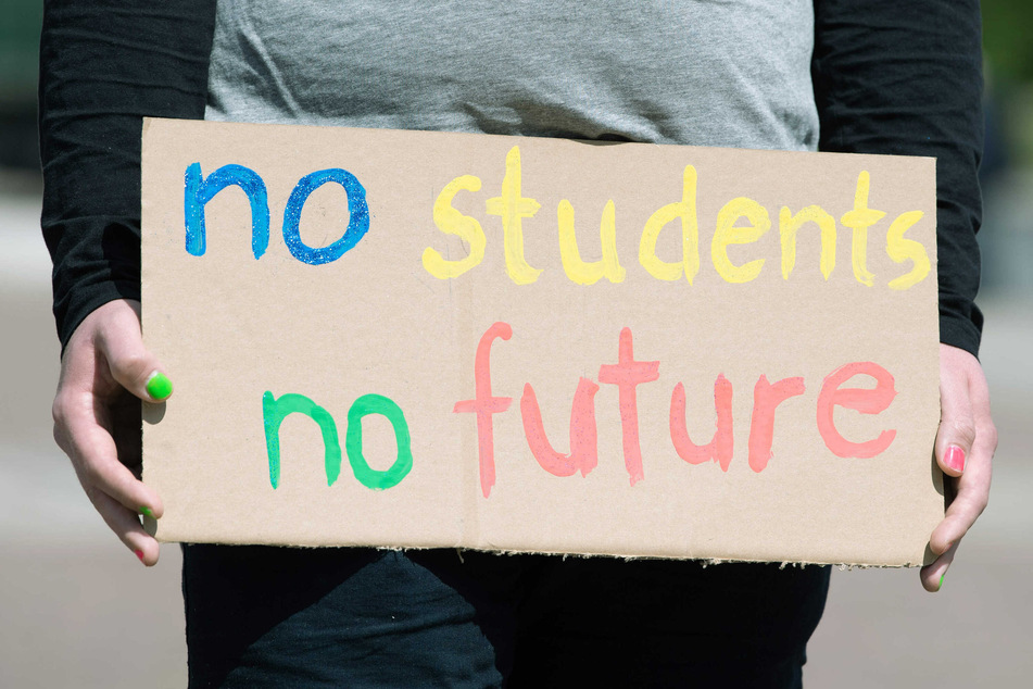Eine Studentin trägt ein Schild, auf dem "no students – no future" steht.