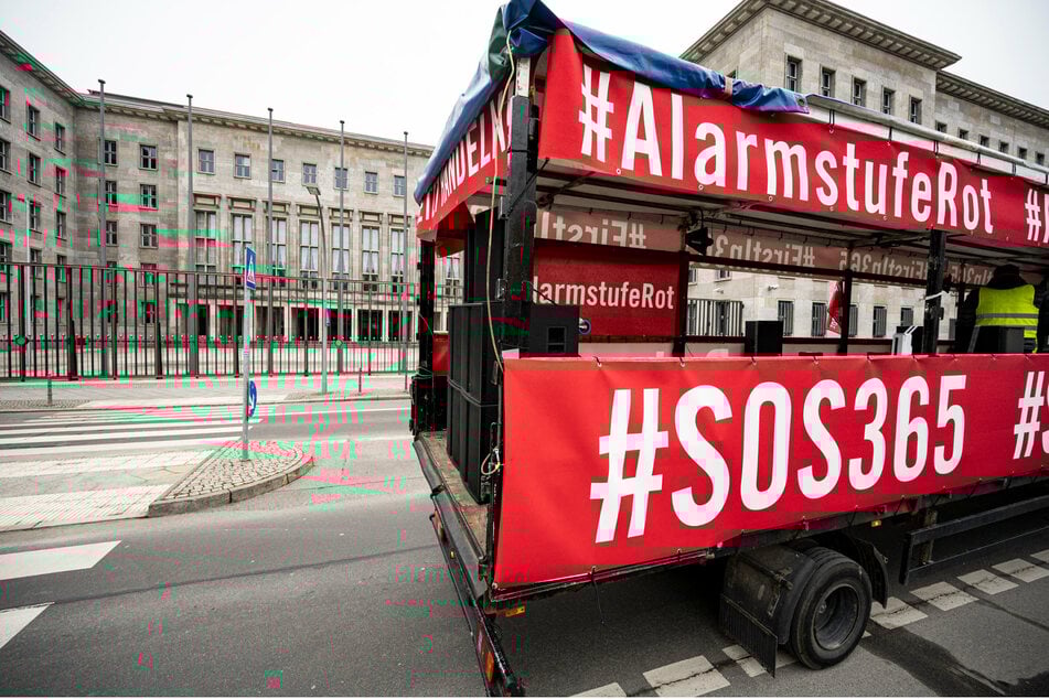 Ein Lastwagen mit Bannern mit der Aufschrift "#AlarmstufeRot" und "#SOS365" fährt bei der Demonstration mit einem Autokorso der Veranstaltungsbranche am Bundesfinanzministerium vorbei.