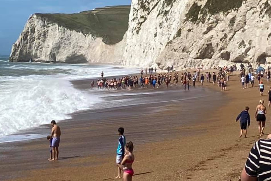 Onlookers watch the heroic rescue operation on the Durdle Door beach in south England.