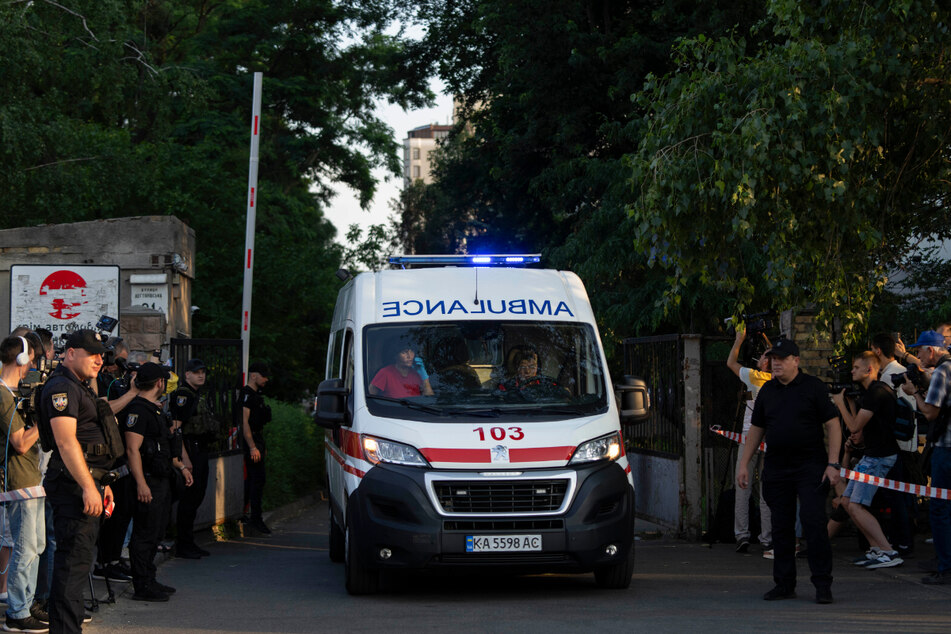 Ein Krankenwagen verlässt das Schewtschenkiwski-Gerichtsgebäude und fährt an Medienvertretern vorbei. In dem Gericht hatte sich ein wegen eines Terroranschlags angeklagter Mann in die Luft gesprengt.