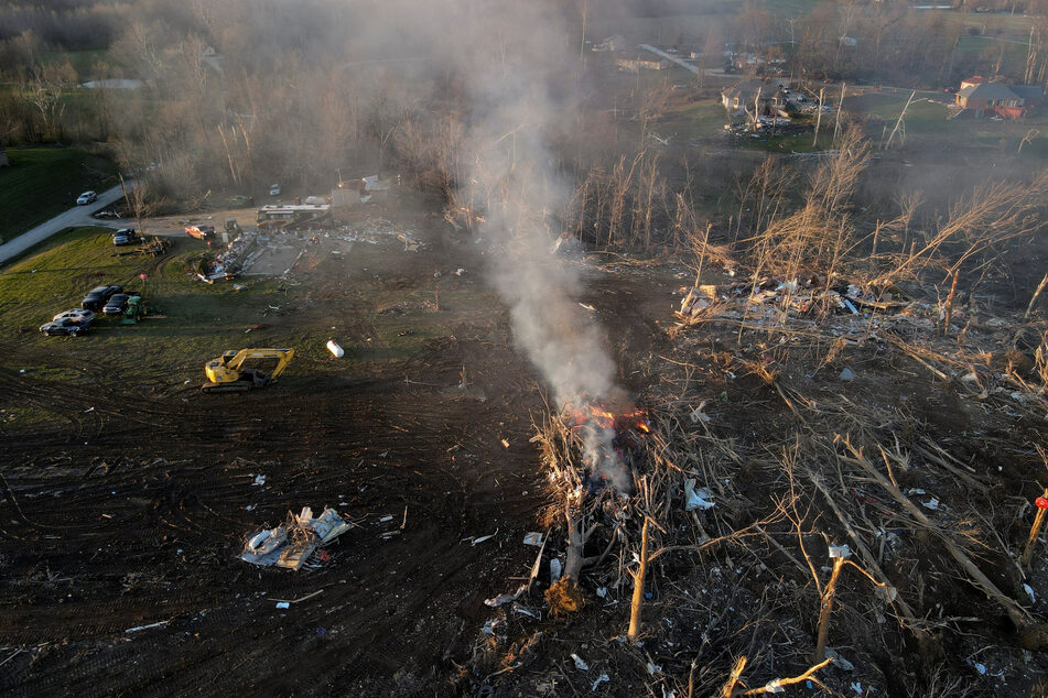 Plumes of smoke from burning piles of wood cleared by work crews rise at the site of severe storm damage in the aftermath of a tornado in Sullivan, Indiana.