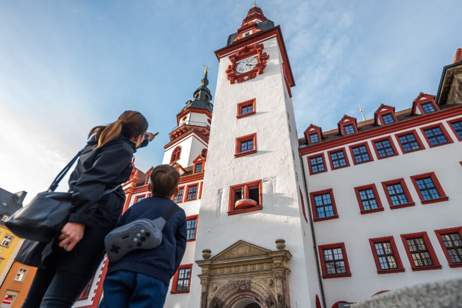 Eine Frau und ein Kind betrachten das Figürliche Glockenspiel am Alten Rathaus.
