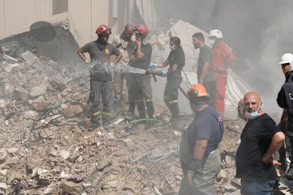 Arbeiter des Zivilschutzes löschen ein Feuer, während Rauch vom Ort des israelischen Raketenangriffs vom Freitag in den südlichen Vororten von Beirut aufsteigt.