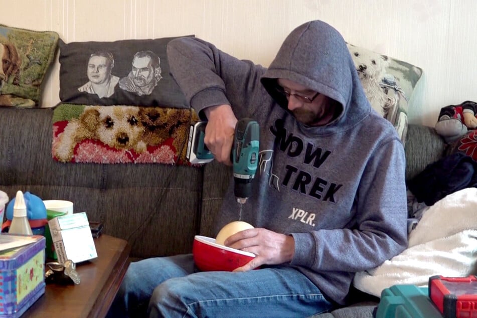 Tino (46) bohrt Löcher in die dicke Schale.