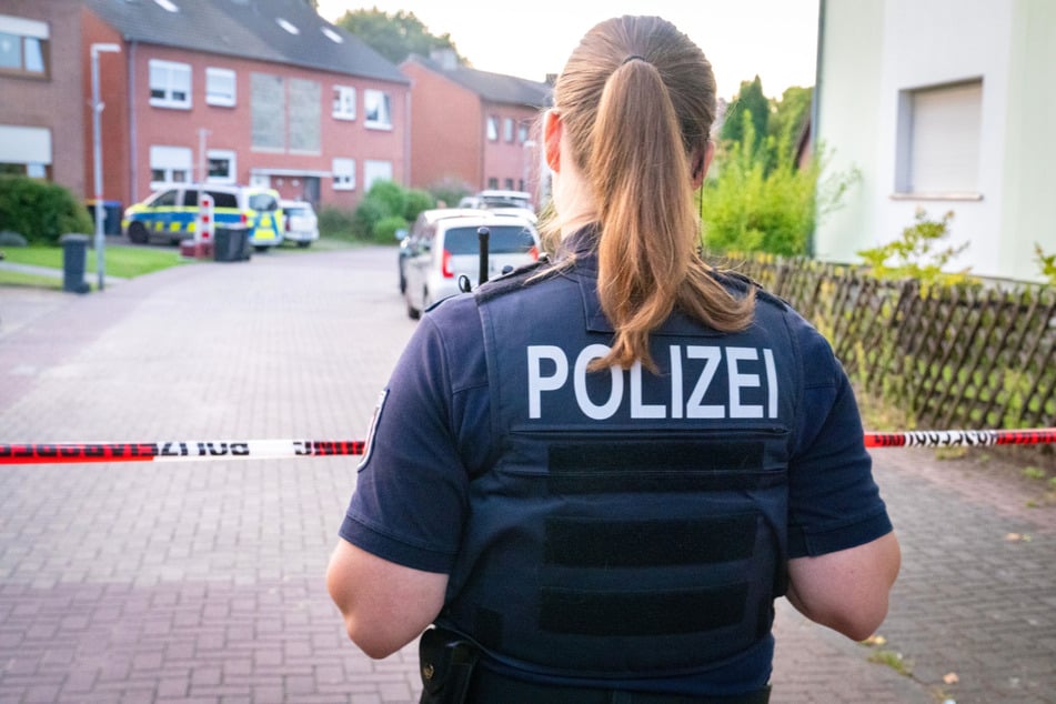 Eine Polizistin steht am Tatort in einem Wohngebiet im Norden von Moers vor einem Absperrband.