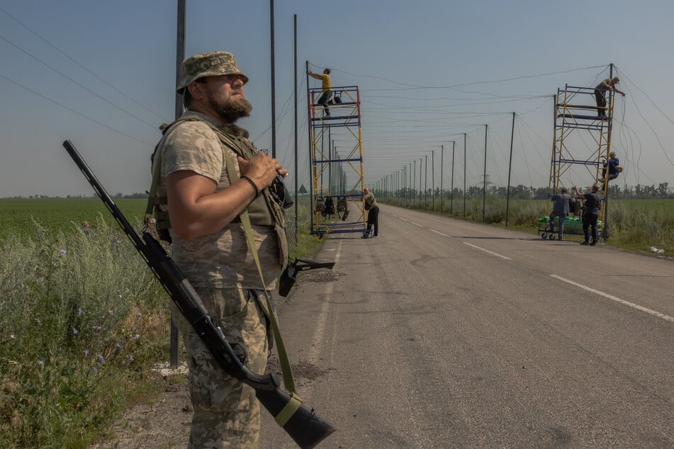 Irgendwo im Donbass: Ein ukrainischer Soldat mit Schrottflinte hält Ausschau, während seine Kameraden die Straße drohnensicher machen.