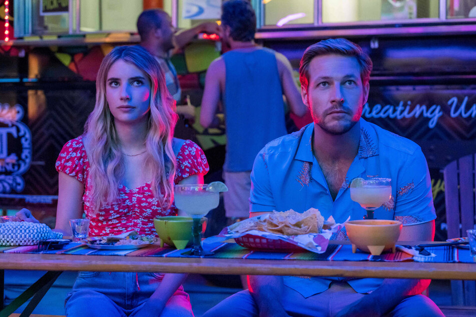 Emma Roberts (l.) and Luke Bracey (r.) play two strangers who give love a try in Holidate.