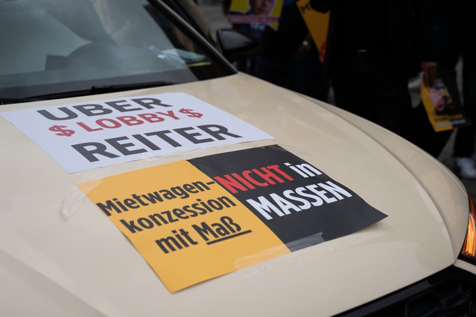 "Mietwagenkonzession mit Maß - Nicht in Massen" klebt auf einem Taxi in München.