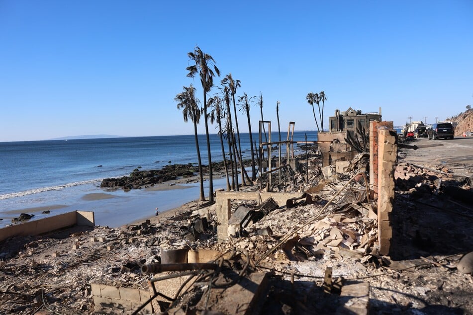 The charred remains of palm trees and homes are seen along Pacific Coast Highway in Malibu, California, as the Palisades Fire continues to grow on Sunday.