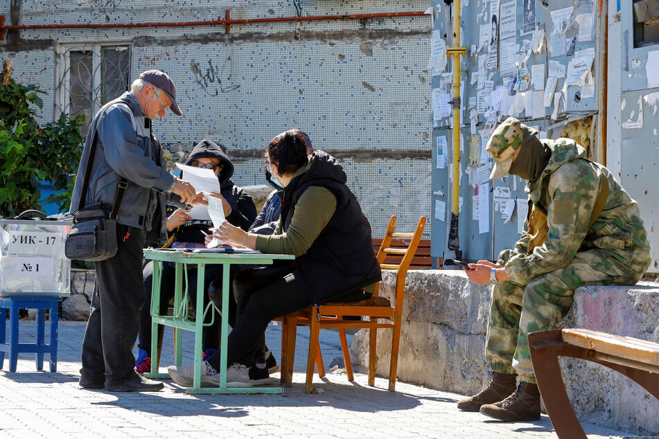 A pro-Russian service member sits next to a mobile ballot box set up in Mariupol.