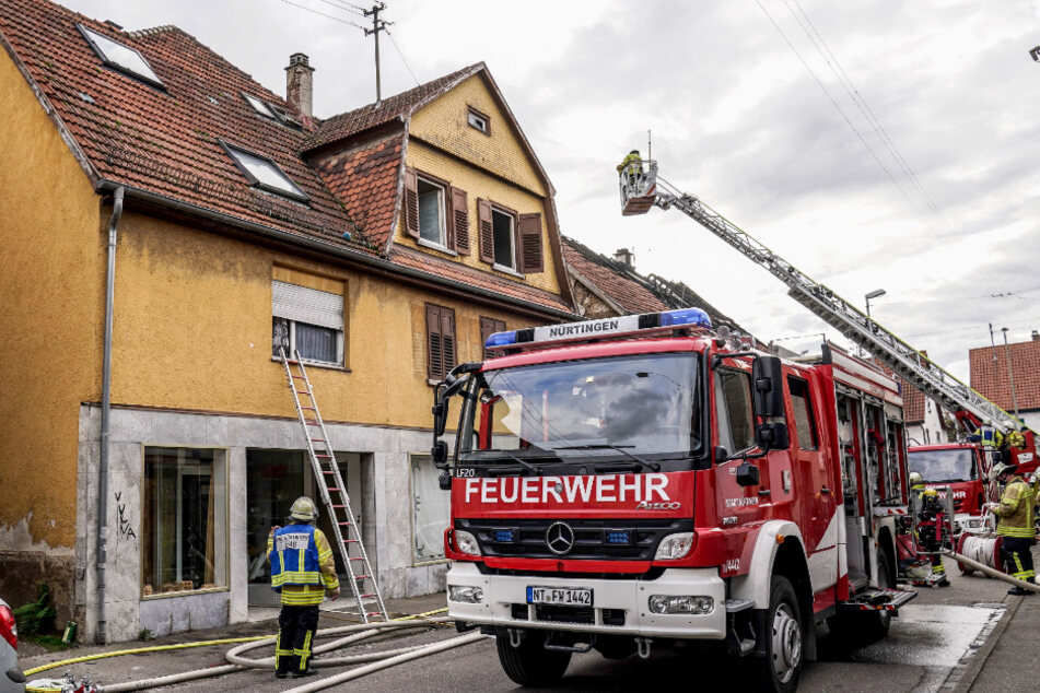 Einsatzkräfte der Feuerwehr und des Rettungsdienstes arbeiten an einem Brand in einem Wohnhaus. Zuvor hatte es im Nachbargebäude gebrannt.
