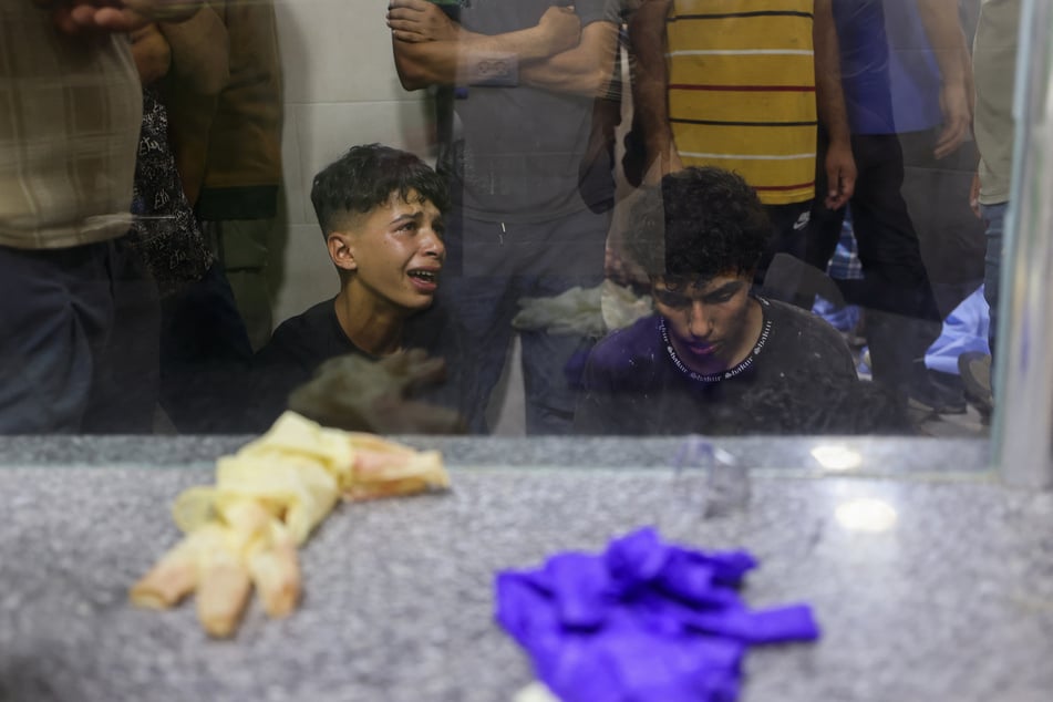 Palestinian children mourn by the body of a relative killed in Israeli fire at a food aid distribution point set up by the Gaza Humanitarian Foundation, at Al-Awda hospital in the Nuseirat refugee camp in the central Gaza Strip on June 24, 2025.