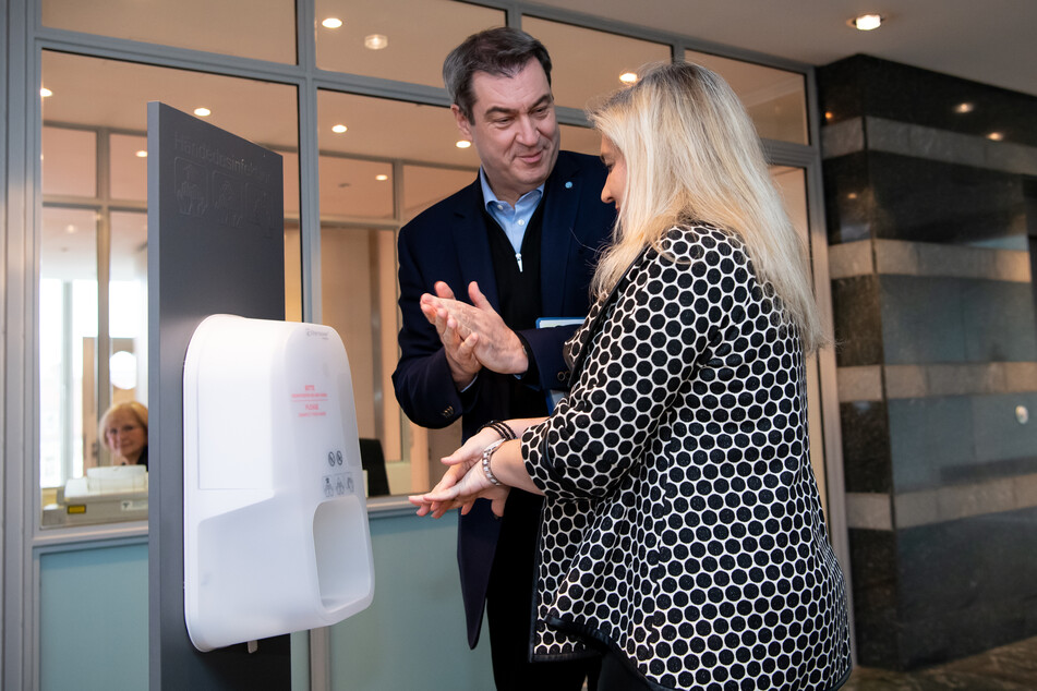 Markus Söder (CSU), Ministerpräsident von Bayern, und Melanie Huml (CSU), Gesundheitsministerin von Bayern, desinfizieren sich vor Beginn einer Sitzung des bayerischen Kabinetts die Hände.