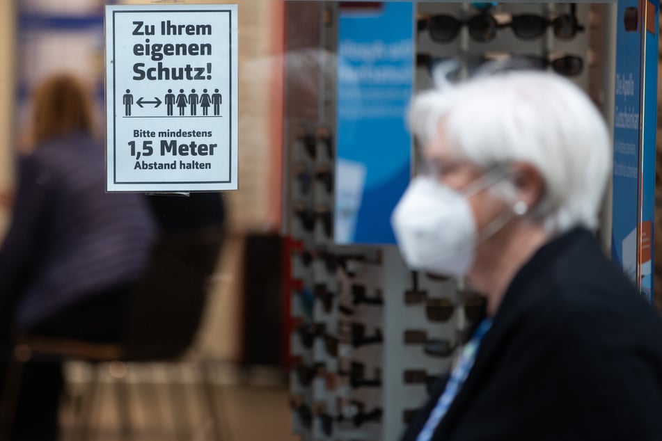 Eine Frau mit Mundschutz geht an einem Geschäft vorbei.