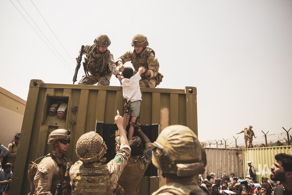 Britische und türkische Koalitionstruppen helfen im August 2021 zusammen mit US-Marines einem Kind während einer Evakuierung am Hamid Karzai International Airport.