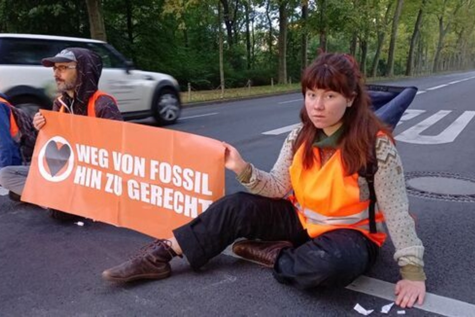 Auf der Puschkinallee in Berlin kleben Klimaaktivisten auf dem Asphalt.